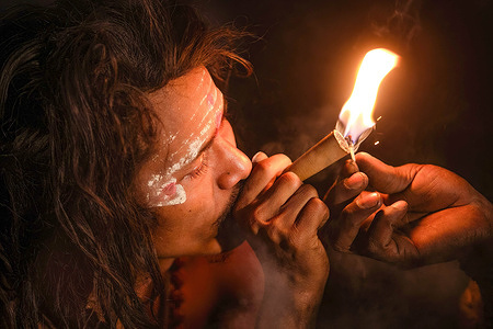 A Hindu holy man, or Sadhu, the follower of Lord Shiva, smokes marijuana on the eve of the Maha Shivaratri festival at the premises of Pashupatinath Temple in Kathmandu. Hindu Devotees from Nepal and India come to this temple to take part in the Shivaratri festival which is one of the biggest Hindu festivals dedicated to Lord Shiva and celebrated by devotees all over the world.