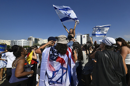 A woman is waving an Israeli flag as people await the arrival of the released Israeli hostages at the hospital. The people of Israel celebrated the release of the hostages after two years in Hamas captivity, marking the end of the war. Crowds gathered at hospitals to welcome the final hostages returning home, as the nation danced and rejoiced in relief and happiness.