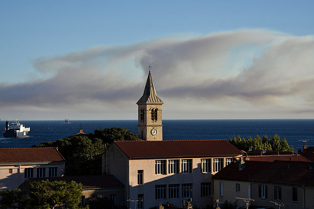 Smoke from the fire seen in the sky above the sea beyond the houses. With strong winds, heat and drought, the Bouches du Rhône region has been placed on a red fire alert. Several fires have been reported particularly in Martigues where the fire has covered more than 240 hectares and threatened 120 homes.