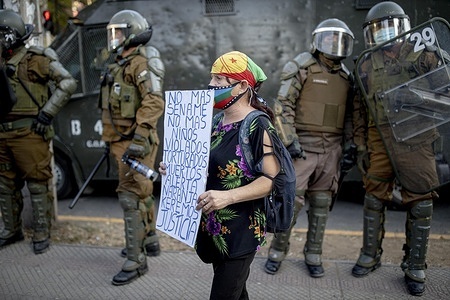 A protester stands in front of the riot police with a placard with slogans against SENAME (national children's service) and the alleged acts of violence during the protest.
Protesters took to the streets outside a SENAME (national children's service) home interrupting traffic in a massive protest against Sename after a video was released denouncing an alleged mistreatment of a minor in the Carlos Antúnez Family Residence which is run by SENAME.