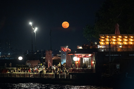 People seen sitting in a cafe on the Sarayburnu beach during the full moon.