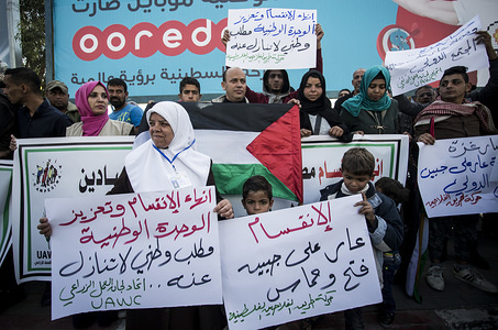 Palestinians are seen holding placards and a banner during the to end the split in Gaza City.