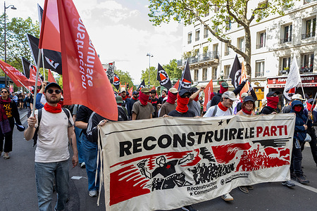 Demonstrators, many wearing red face covering seen carrying a banner reading "RECONSTRUIRE LE PARTI" with revolutionary imagery during the May Day march. Trade unions and political organizations in Paris gathered for the annual May Day manifestation to advocate for labor rights, social protection, and improved working conditions. The inter-union procession moving from Place de la République to Place de la Nation was marked by diverse social demands and a significant security presence in Paris on May 1, 2026.