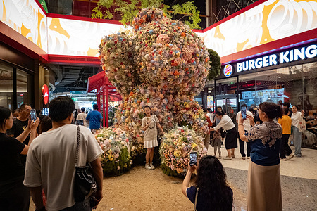 A large floral sculpture attracts many people in the mall. During China's National Day and Mid-Autumn Festival holiday, many people choose to visit malls for leisure. Festively decorated malls offer food, entertainment and shopping, making them a popular relaxed choice.
