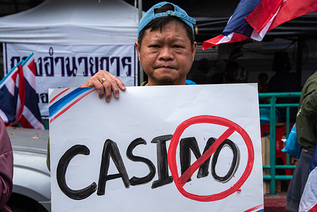A protester holds a placard reading "Casino" during the demonstration outside the government house in Bangkok.. Protesters gathered outside government buildings to oppose Thailand's plan to legalize casinos and entertainment complexes nationwide, a move aimed at boosting tourism and investment.