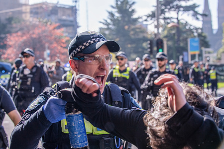 A police officer shouts get back as he deploys his crowd control spray on an anti-fascist protester during the demonstration. A day of political tensions and clashes unfolded in Melbourne as a far-right Neo-Nazi group held an anti-immigration rally at state parliament and was met with fierce opposition from left-wing anti-fascist counter-protesters. Riot police were deployed as scuffles broke out between the two groups, with pepper spray and horses used to control the crowd. Protest signs demanding inclusivity, diversity, and social justice were held high in a show of unity against hate speech and discrimination. The clashes highlight the deep political divide and social issues surrounding immigration policies and the fight against racism in Melbourne and beyond.