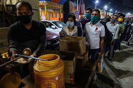 Devotees wearing masks as a preventive measure against the spread of covid-19 in a queue to collect their food at Gangasagar Transit Camp in Kolkata.
Gangasagar transit camp in Babughat, Kolkata is filling slowly with the presence of devotees before the holy bath of Sankranti amid COVID-19 restrictions. Number of devotee is very less compared to previous years.