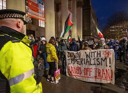Hands off Iran pro-regime supporters with anti war supporters hold a banner during the rally. Manchester centre with a stand off between supporters of Iranian regime change with USA and Israel military action and supporters of the existing regime and the deceased Ayatollah Ali Khamenei. The pro regime supporters were joined by Manchester Stop the War members. The two crowds were kept apart by police.