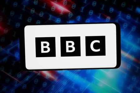 In this photo illustration, the logo of British Broadcasting Corporation (BBC) is displayed on a smartphone in front of abstract background on computer screen.