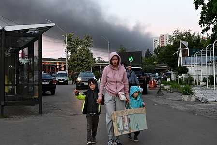People return from a shelter against a backdrop of black smoke in the sky after Russian shelling.