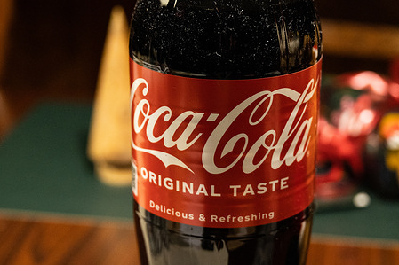 In this photo illustration, a Coca-Cola bottle is seen displayed on a table.