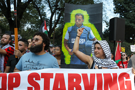 Demonstrators are seen at a pro-Palestine protest, with a poster in the background honoring Palestinian journalist Anas al-Sharif, who was killed by the Israeli army in Gaza on August 10, 2025. Pro-Palestine demonstrators, some coming from major East Coast cities, marched in Manhattan, New York City, on August 16, 2025, to denounce the genocide in Palestine and the killing of journalists in Gaza.