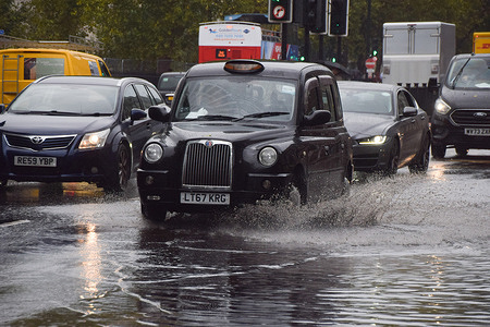 Cars and taxis pass through a waterlogged Euston Road as heavy rain drenches the capital.