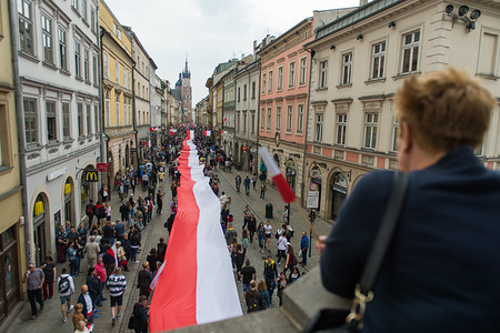People hold a polish flag along the royal road during the National Flag day at the Main Square in Krakow. City scouts, today attempt to break the national record along the length of the national flag. A polish flag with 3 meters wide and more than two kilometers long occupy all the royal road, from the Florian Gate to the Wawel Hill.