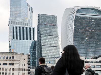People walk on London Bridge in front of City of London skyscrapers.