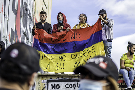 Protesters holding a Colombian flag saying "Who doesn't love her country doesn't love her mother" during the demonstration.A month after the national strike first began, protesters continue to demonstrate on the streets of the Colombian capital, Bogotá and all over the country to oppose government policies and police violence. Multiple demonstrations and marches are taking places every day with thousands of people participating in the strike.