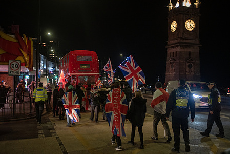 Far-right protesters march with flags by the Clock Tower during the rally. Kent Anti-Racism Network, Care4Calais and the Stand Up To Racism staged a counter-protest with a large number of attendees against the UKIP anti-immigration demonstration in Margate, UK.