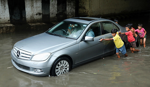 Kids seen pushing a car through a waterlogged Zakhira underpass area after heavy rainfall in New Delhi.Delhi Traffic Police closed several underpasses and roads to avoid traffic due to heavy rainfall and water logging in many areas including Indira Gandhi International Airport. Indian Meteorological Department (IMD) announced thunderstorms with very heavy intensity rain in the Capital.