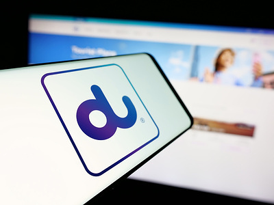 In this photo illustration, a smartphone with the logo of Emirates Integrated Telecommunications (du) is seen on screen in front of website.
