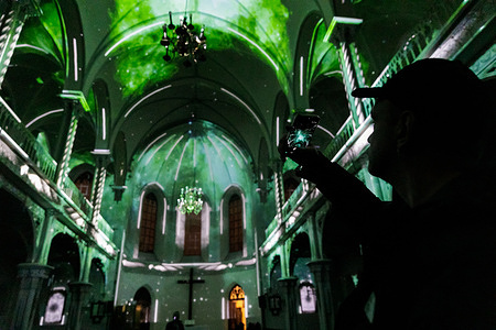 A man records a light show on his smartphone during the Eonarium immersive exhibition at the Evangelical Reformed Church. An immersive light and sound exhibition featuring 3D video mapping projections adapted to the architecture of the venue is presented inside the Evangelical Reformed Church in Warsaw, Poland. The exhibition is part of an international tour previously shown in Switzerland, Germany and France.