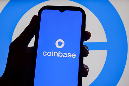 In this photo illustration, The Coinbase logo is displayed on a mobile phone with the company branding visible in the background.