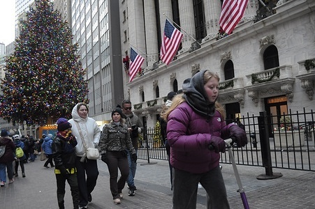 A person rides a scooter past the New York Stock Exchange, which is seen next to a Christmas tree in the Financial District in Manhattan, New York City.