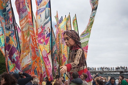 Little Amal crosses the Millennium Bridge.
Little Amal is a giant puppet refugee that represents a 9-year-old Syrian girl who is welcomed at St Paul's Cathedral, London. The puppet's journey from Turkey to the UK highlights the trail that has been used by many refugees looking to escape war and start a new life. Little Amal has travelled over 8000km to try to reach safety.