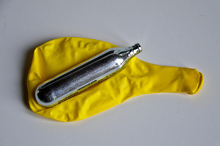 In this photo illustration, a yellow balloon and a nitrous oxide cartridge are placed on a white table. Nitrous oxide, nicknamed "laughing gas", is a new drug that is attracting more and more adolescents.