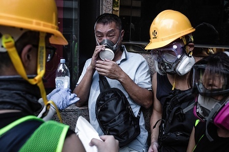 A man is being helped by the first aid crew and protesters after feeling dizzy with teargas during a pro-democracy march.Protesters continue to demonstrate across Hong Kong for the 15th consecutive week. After marching for few hours from Causeway Bay towards Admiralty, clashes between protesters and riot police occurred in different parts of the island. Chief Executive Carrie Lam withdraw the polemic extradition law and protesters now call to the government to attend the rest of their demands, including an independent inquiry into police brutality, the retraction of the word 'riot' to describe the rallies, and genuine universal suffrage.
