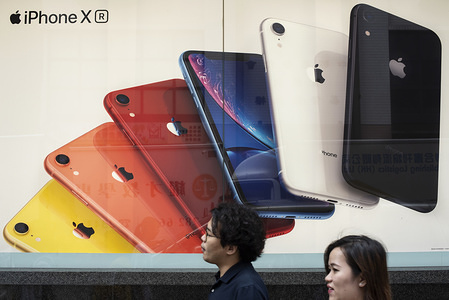 Pedestrians walk past an Apple Iphone advertisement in Hong Kong.