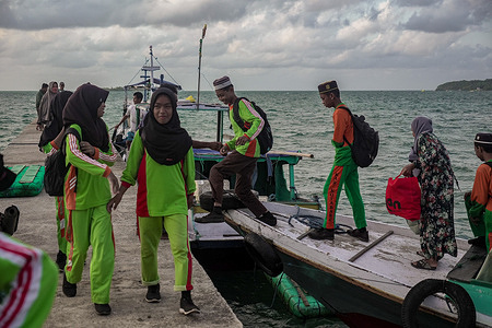 Elementary school students step off a boat after crossing from nearby islands to reach their school in Teluk Tamiang, a remote area in South Kalimantan. The lack of basic educational infrastructure in remote regions has sparked criticism of the Indonesian governmentís priority programs, such as free nutritious school lunches and Smart TV installations, which some argue overlook more urgent needs like proper school facilities and transportation.