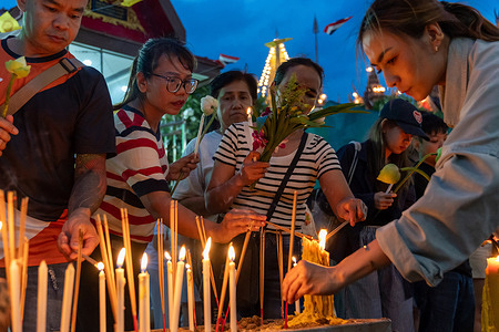 A view of a group of people lighting candles and incense sticks at Wat Lat Phrao Temple in Bangkok. Asalha Bucha Day marks the Buddha's first sermon and the formation of the Buddhist monastic community, known as the Sangha. Devotees across Thailand gather at temples for candlelight processions, meditation, and merit-making.