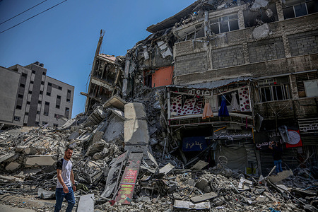 A Palestinian walks past the rubble piled up in Gaza, following the ceasefire agreement between Gaza and Israel.
The ceasefire between Gaza and Israel has been implemented.