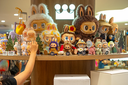 A customer picks a Labubu from a display shelf at a Pop Mart shop at the Siam Center. The store opened on July 17th, 2025.