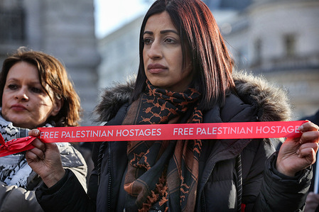 A protester holds a red ribbon with the words "Free Palestinian Hostages" during the demonstration at Piccadilly Circus in Central London. The Red Ribbons campaign is a global campaign highlighting the plight of Palestinians held in detention by Israel. Of the nearly 9100 Palestinians currently detained, it is estimated that almost a third are effectively treated as hostages, abducted and denied even the bare minimum of legal rights. People are taken from their beds and elsewhere and disappear for indefinite periods without charges or court hearings. This number includes 400 children.