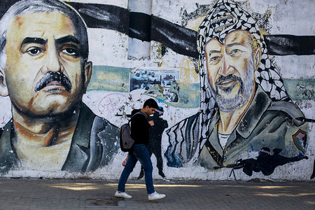 Palestinian youth walking past a mural depicting the late Palestinian leader, Yasser Arafat and the leader of the Popular Front, George Habash in Gaza City.