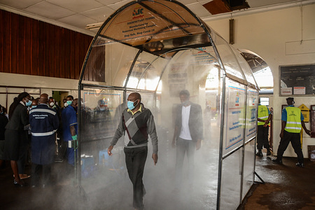 Commuters pass through a disinfectant tunnel that disinfects the whole body at Nairobi Railway Station while wearing face masks as a precaution against the spread of Coronavirus.Kenya has so far confirmed 411 cases of the Coronavirus,150 recovered and 21 death.