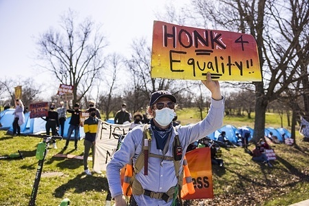 Marc Teller holds a sign asking passers by to “Honk 4 Eqality” during a protest near Assembly Hall. A coalition of Bloomington community members, activists, and Indiana University students march from Dunn Meadow to Simon Skjodt Assembly Hall during the “March to end the Madness” to protest against the City of Bloomington’s treatment of unhoused residents pitching tents on public property and the 10 million dollar severance payment Indiana University will have to pay fired men’s basketball coach Archie Miller. Several games for the NCAA basketball tournament were being played inside Assembly Hall, including the St. Bonaventure vs. LSU game that took place during the protest.