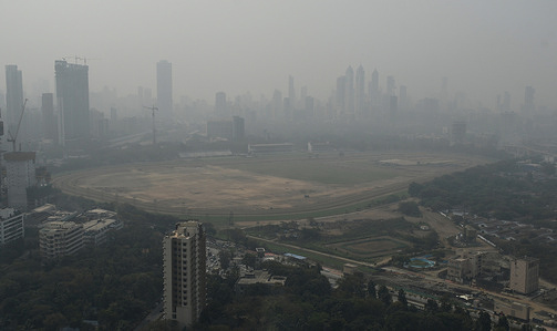 A view of high rise buildings in the distance covered in smog in Mumbai. Air quality in the city remains largely in unhealthy or severe category due to pollution mainly arising from the dust from construction site and ongoing infrastructure projects and smoke emission from vehicles passing on the road. winter months (November to February) typically see worse air because low wind speeds and temperature inversions trap pollutants, preventing them from dispersing.