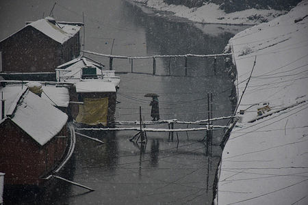 A woman walks towards her houseboat during snowfall in Srinagar. Kashmir valley was cut off from the outside world, with all flights to and fro Srinagar airport getting canceled and the national highway being shut off due to heavy snowfall on Monday morning.