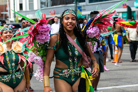 A participant seen in a costume and regalia covered in bright colors and gems representing a carnival theme as the Edmonton Cariwest parade rolls through downtown Edmonton. The Cariwest festival celebrates the heritage and culture of the islands of the Caribbean.