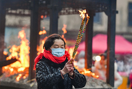 A woman burns incense and prays for good luck at the Zifu Temple in Fuyang City on the first day of the first month of the Chinese lunar calendar.