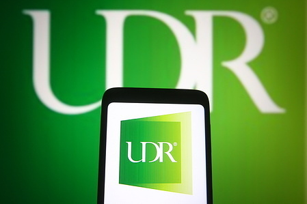 In this photo illustration, UDR, Inc. logo of a real estate investment trust company is seen displayed on a smartphone and a pc screen.