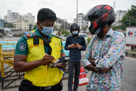 Police officer stops a motorcyclist at Pragati Sarani road checkpoint during the covid-19 lockdown in Dhaka.
Bangladesh enacted a lockdown on July 1st in an effort to contain a third wave of Covid-19, as cases have surged, fueled by the Delta variant first detected in neighboring India.