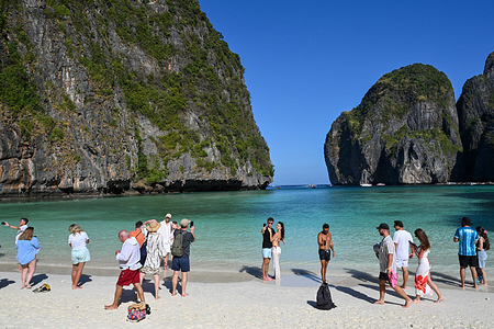 Tourists gather along the beach and take pictures at Maya Bay on Thailand's Phi Phi Leh Island.