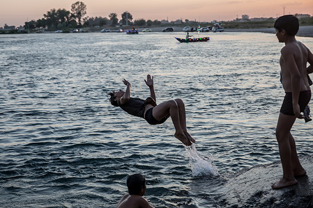 Children swim in the Euphrates river at dusk, beside the city of Raqqa. The Euphrates is the longest river in West Asia.