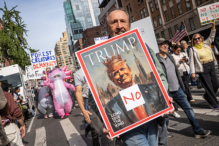 A protester holds a sign of a mock Time Magazine cover during the "No Kings" national day of protest against Donald Trump and the current administration.