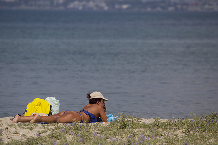A woman is seen relaxing on the beach sand.
Daily life in Perea, a beach town near Thessaloniki, just 5 minutes from the airport and 15 from Thessaloniki city center. It has a long sandy beach offering hotels and everything that is needed for holidays. There is a little ferry boat and buses connecting Perea beach to Thessaloniki.