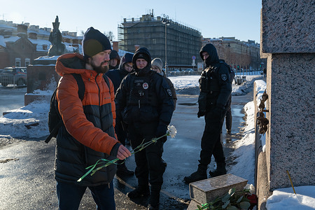 Police watch a man as he lays flowers at the Memorial to the Victims of Political Repressions in St. Petersburg in memory of Russian opposition leader Alexei Navalny on the first anniversary of his death. On the first anniversary of Alexei Navalny's death on February 16, 2024, his legacy and the circumstances of his passing remained in focus. Supporters laid flowers at his grave in Moscow, while others gathered at the Memorial to the Victims of Political Repressions, highlighting the link between his fate and Russia’s history of political persecution.