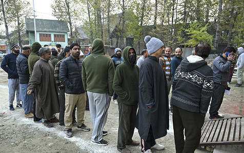 People queue outside a polling station to to cast their votes during the by-election for the Budgam Assembly seat. Authorities deployed additional forces to ensure smooth voting as residents cast their ballots amid tight security and cold autumn weather.